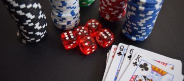 chips, dice and cards lay on a black surface