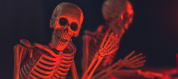 A living skeleton waving his hand with a red light flashing his skull