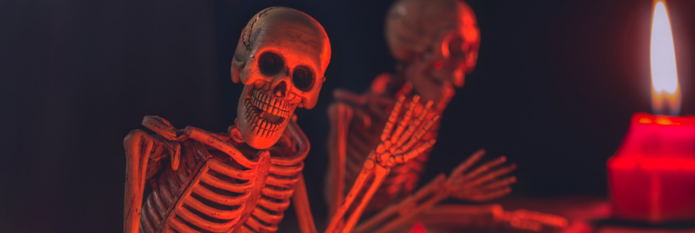 A living skeleton waving his hand with a red light flashing his skull